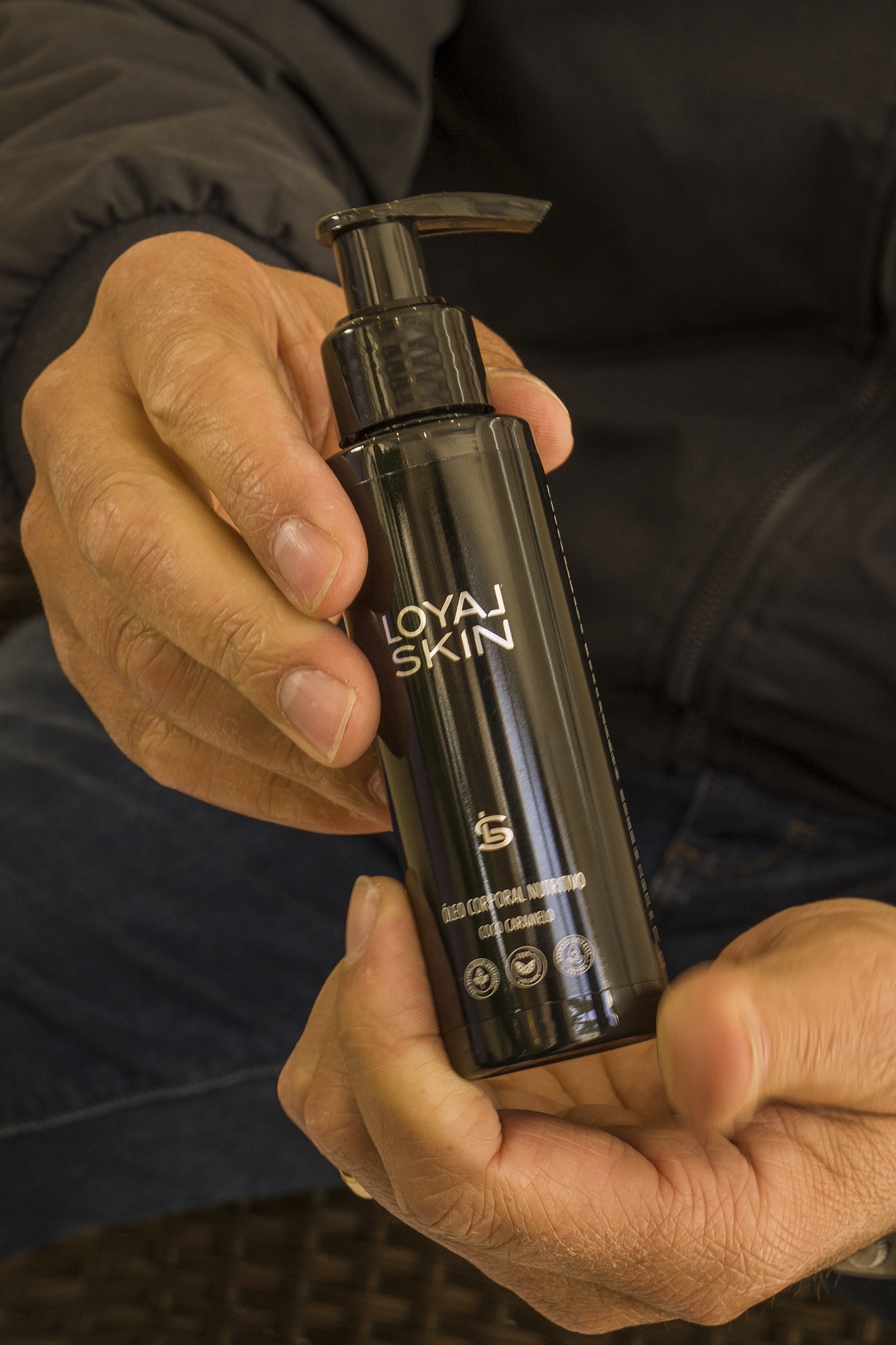 Mãos de um homem a segurar o frasco do Óleo Corporal Loyal Skin